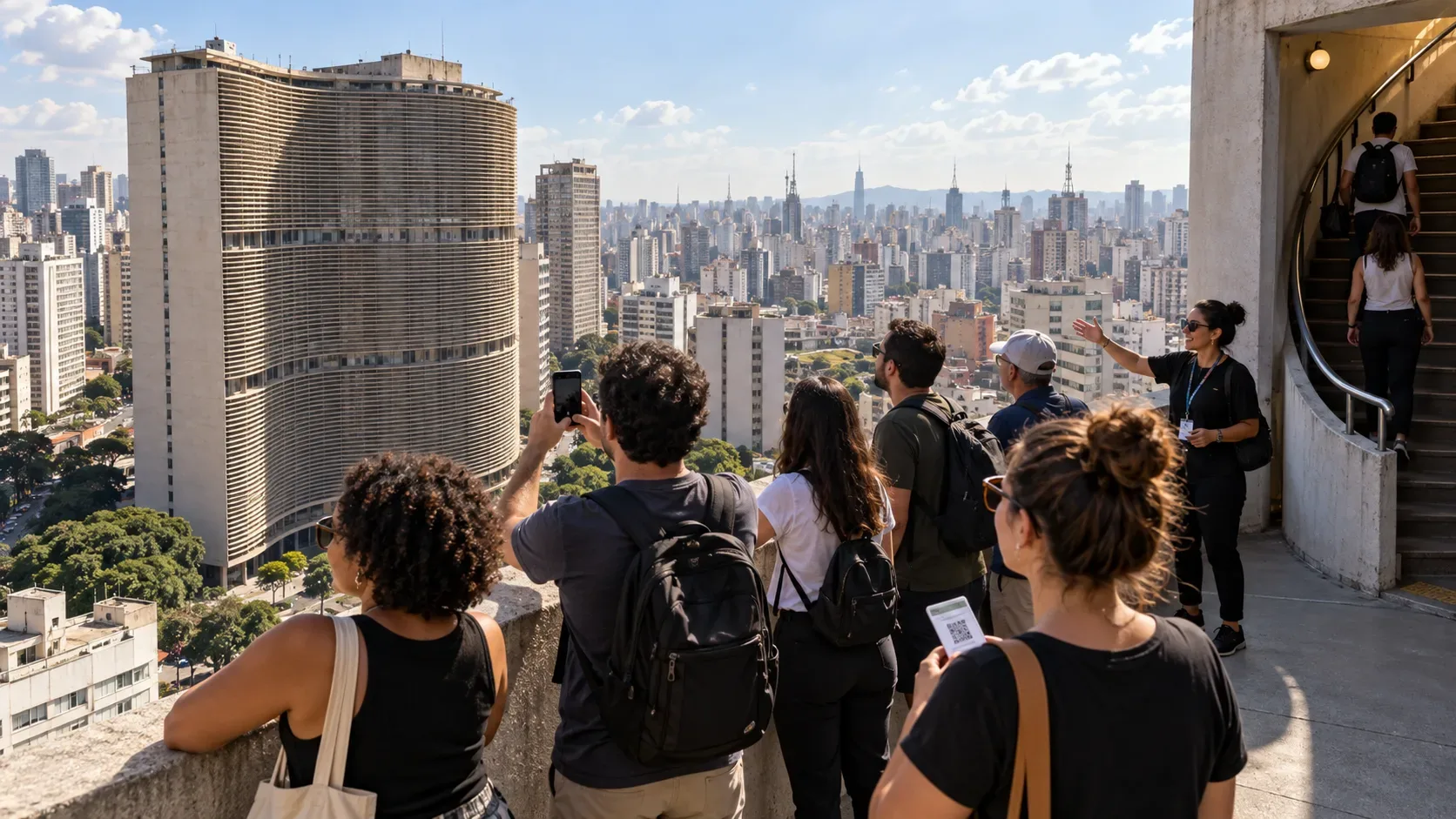 Grupo de visitantes em terraço elevado com vista para o Edifício Copan e o skyline de São Paulo, com escada de acesso ao lado.